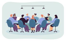 Imagem de uma mesa de reunião, com pessoas sentadas em volta