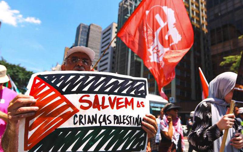 CUT-SP Fotografia mostra homem com cartaz pedindo para salvar as crianças palestinas