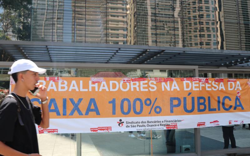 Homem passa em frente a faixa estendida no local onde o ato foi deflagrado, na Avenida Paulista Foto: Contraf-CUT