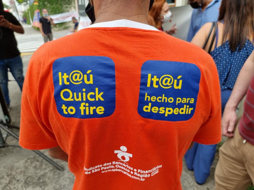 Foto homem vestido com camiseta laranja, com os dizeres  "Itaú, Quick to Fire, e Itaú hecho para despedir"
