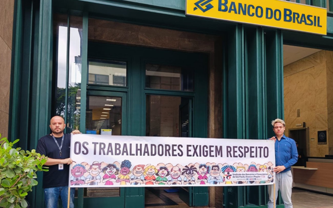 Dia Nacional de Luta cobra respeito aos trabalhadores (foto: Seeb-SP) Dirigentes sindicais seguram faixa em frente a agência do Banco do Brasil, onde se lê: Os trabalhadores exigem respeito!
