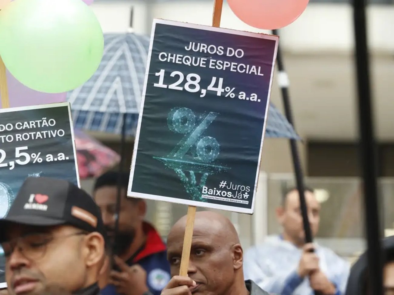 Centrais sindicais fazem manifestação nacional contra os juros altos em frente ao Banco Central na avenida Paulista, em São Paulo, Foto: Paulo Pinto/Agência Brasil Imagem mostra um homem segurando um cartaz onde ser lê Juros do cheque especial 128,4% a.a.#JurosBaixosJá, durante atop das centrais sindicais pela redução dos juros