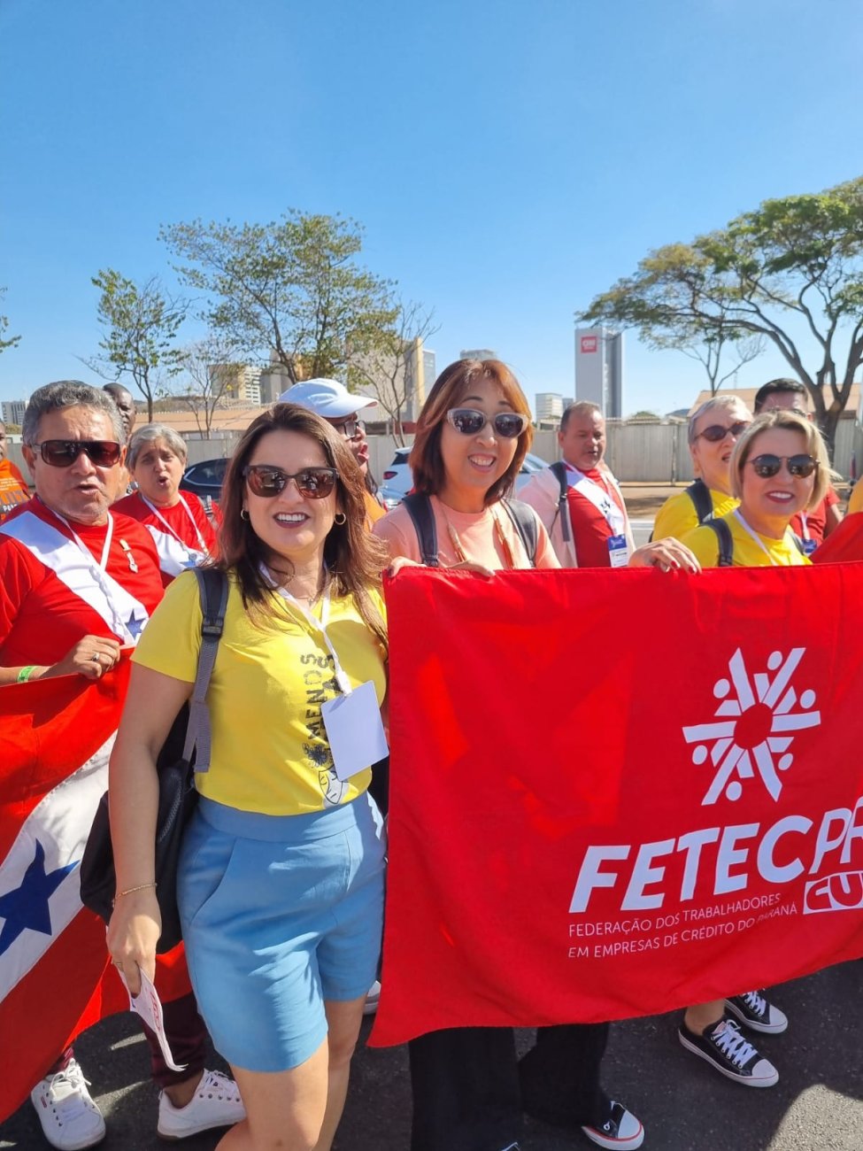 Silmara da Silva, de vermelho, em ato promovido pelo Ministério da Saúde em Brasília Fotografia mostra mulheres, uma de blusa vermelho e outra de amarela, segurando faixa vermelha