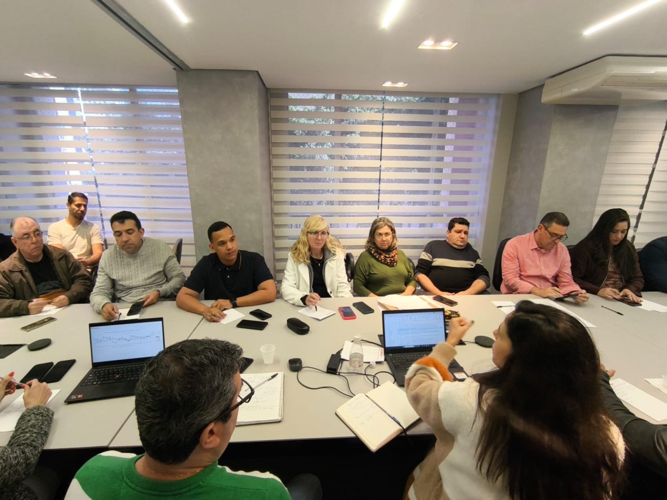 Imagem mostra representantes dos trabalhadores reunidos com representantes do banco, dentro de uma sela e sentados frente a frente em um mesa branca e comprida
