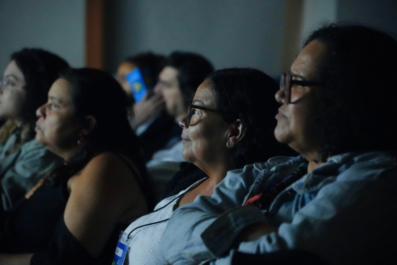 Rosto de pessoas em tela escura durante cinema