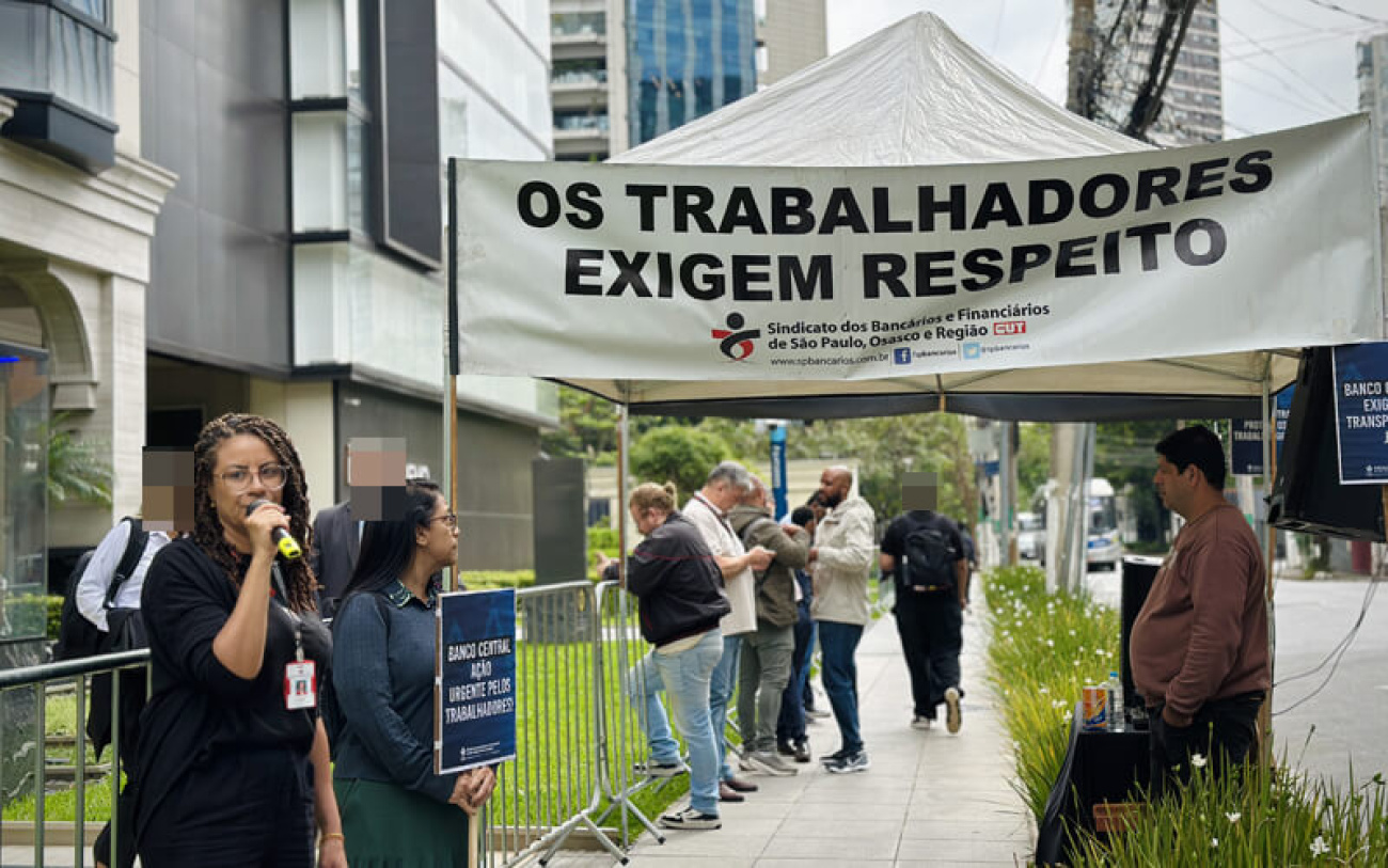 Foto mostra dirigentes em ato em frente ao Banco Master