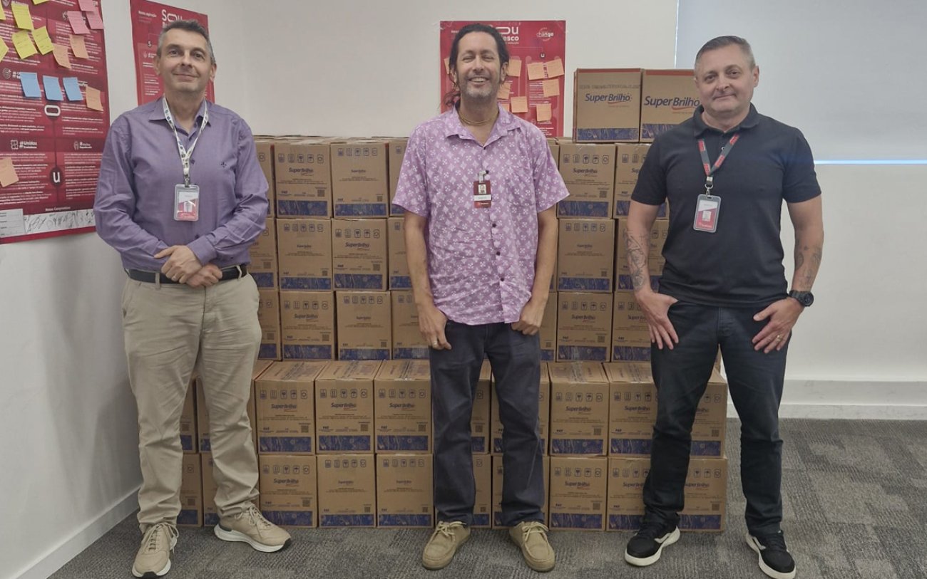Imagem mostra três dirigentes sindicais em frente a dezenas de cestas básicas
