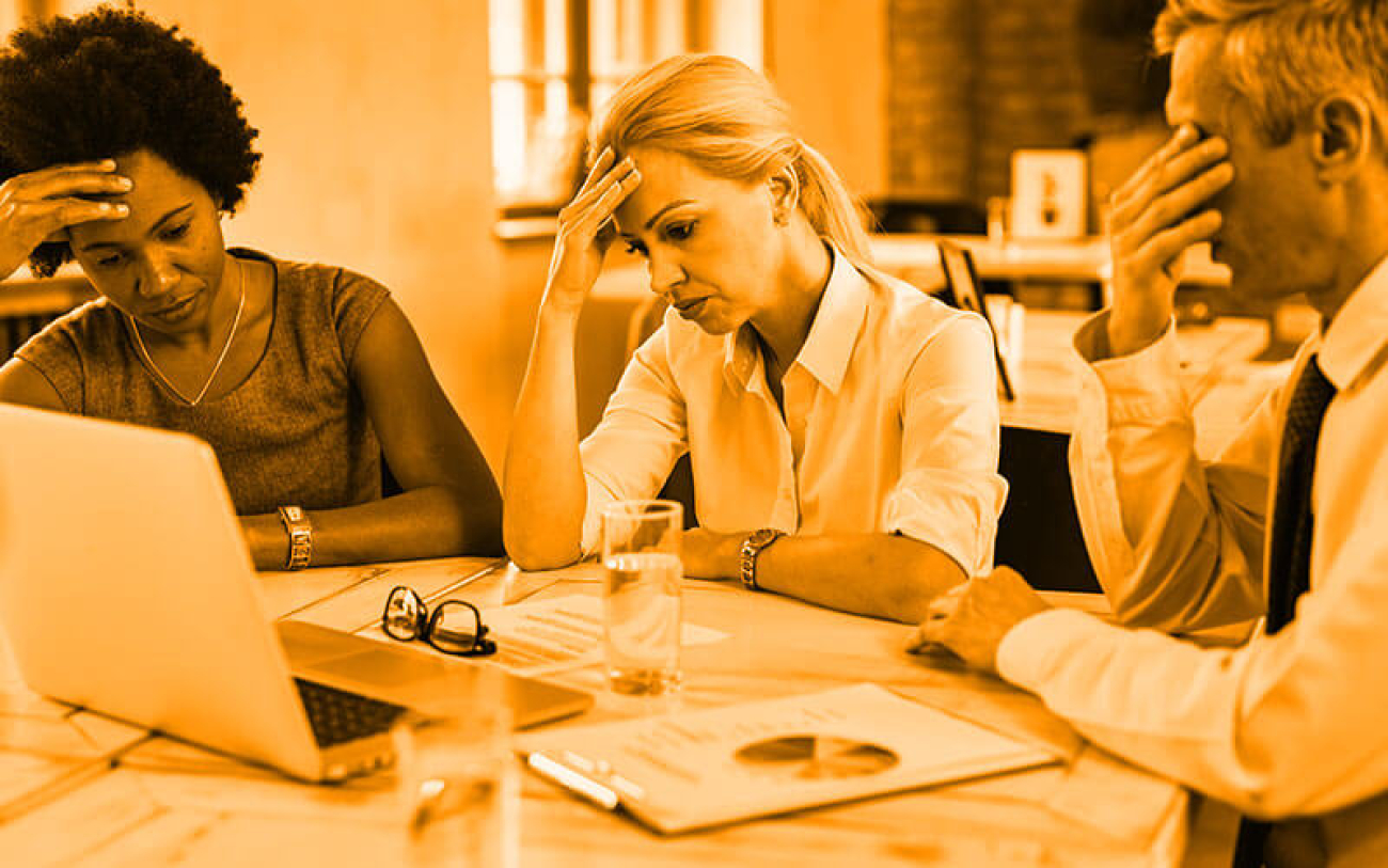 Imagem mostra três pessoas com semblante preocupado em frente a uma tela de computador
