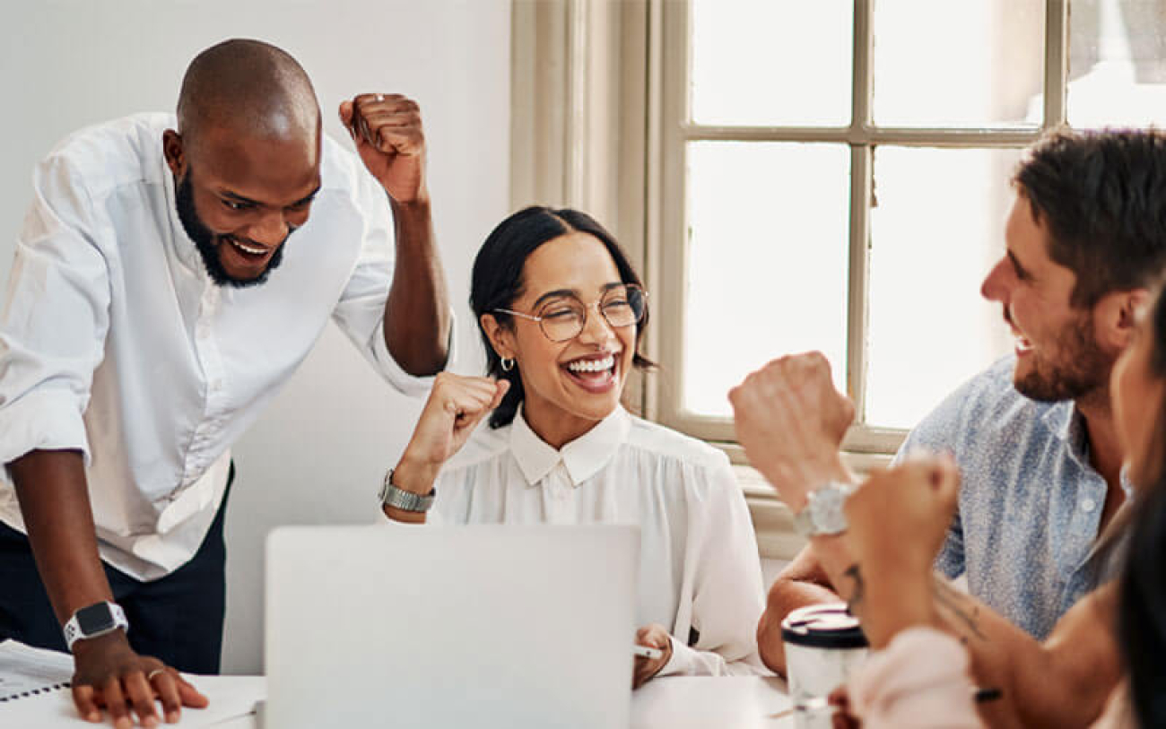 Quatro pessoas em uma sala de trabalho em clima de comemoração