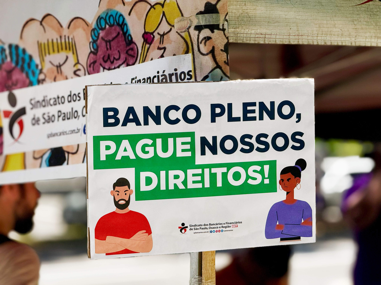 Foto de placa do ato em que se lê: "Banco Pleno pague nossos direitos"