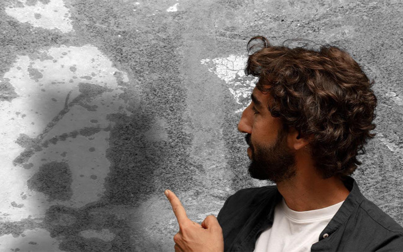 Homem aponta para parede com infiltrações