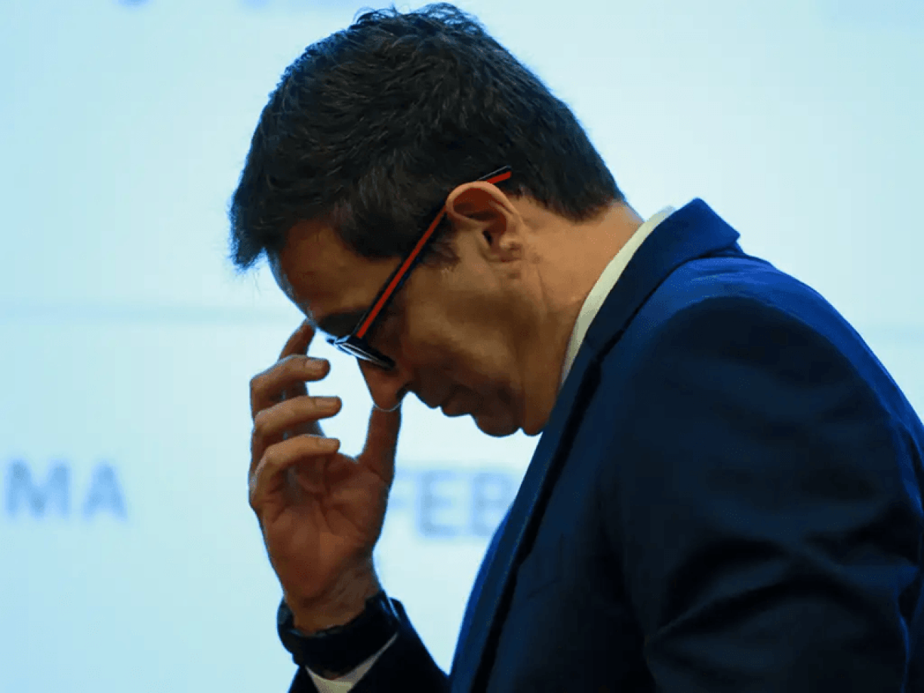 Imagem mostra Roberto Campos Neto, ex-presidente do Banco Central, ele está de cabeça baixa e com os dedos da mão no rosto