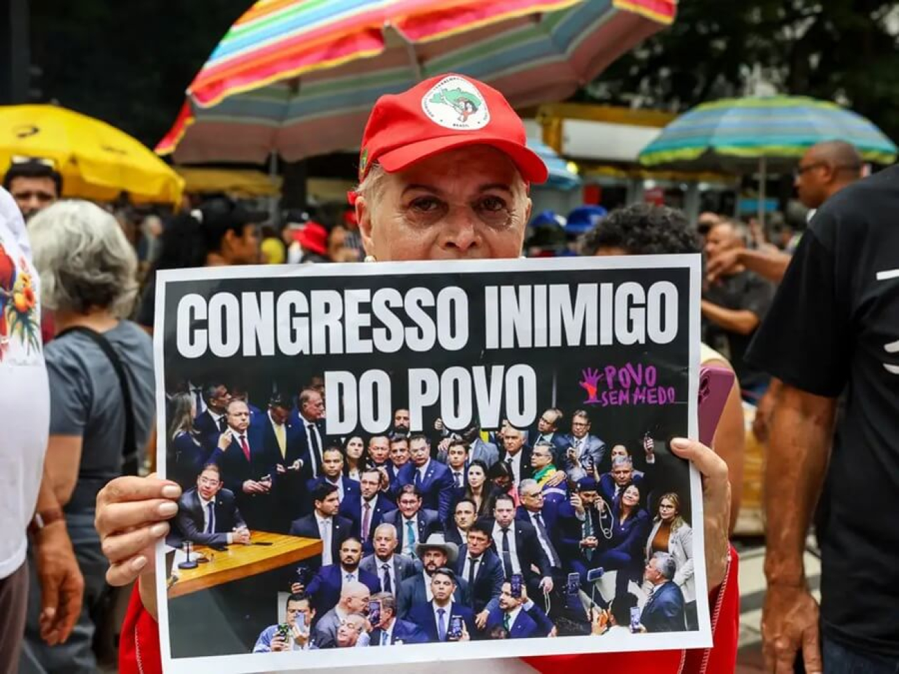 Imagem mostra mulher segurando um cartaz onde se lê "congresso inimigo do povo"