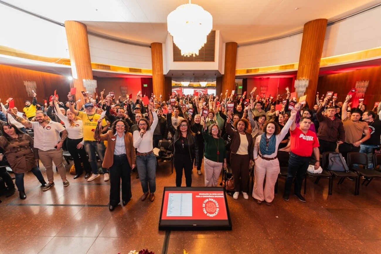 iamgem mostra dirigentes sindicais bancários com crachás levantados durante a conferencia estadual dos bancários