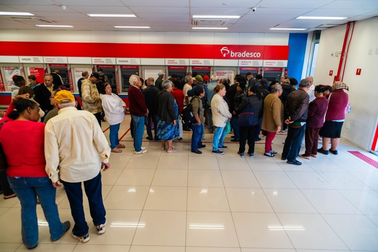 Imagem mostra agêencia lotada de idosos na área do autoatendimento