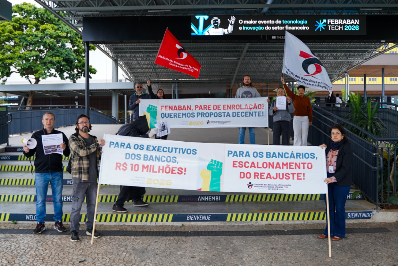 Foto de dirigentes segurando faixas onde se lê: : “Queremos proposta decente” e “Para os executivos dos bancos, R$ 10 milhões. Para os bancários, escalonamento do reajuste”