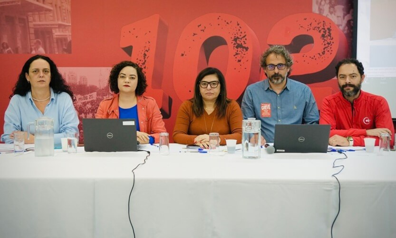 Imagem mostra, sentados em frente a uma mesa e lado a lado Luiza Hansen, Lucimara Malaquias, Neiva Ribeiro, Chico Pugliesi e Leonardo Quadros