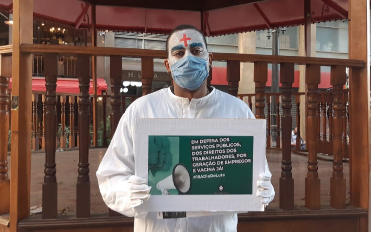 Homem segura cartaz contra PEC 32, por empregos, direitos e vacina já, em ato lúdico promovido pelo Sindicato (foto: Seeb-SP) Homem segura cartaz em protesto por empregos, vacina já, direitos trabalhistas e contra o ataque aos servidores públicos com a PEC 32