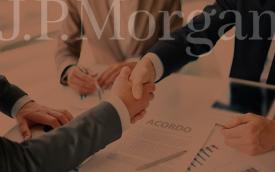Arte composta de uma foto que mostra dois homens vestidos de terno dão as mãos sobre uma mesa. Acima, uma marca d´água com o logo do banco JPMorgan