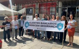 Imagem mostra dirigentes sindicais em frente a uma agência do Santander durante atividade por mais segurança nas unidades bancárias. Os dirigentes portam uma faixa onde se lê "clientes bancários merecem segurança"