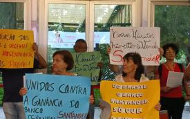 Imagem mostra manifestantes aposentados do Santander portando cartazes