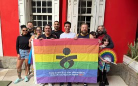 Pessoas atras da bandeira com as cores do arco-iris