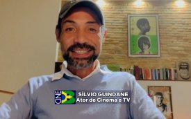 Homem sentado, de pele negra e bone, vestindo camisa azul clara