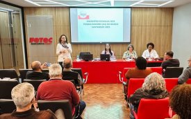 Imagem mostra auditório cheio durante encontro estadual dos bancários do Santander; na frente, a secretária-geral do Sindicato Lucimara Malaquias fala  ao microfone, em pé. Atrás dela, estão sentados em uma mesa Wanessa de Queiroz, Ana Lúcia Ramos e Ana Marta Lima, respectivamente coordenadora da COE Santander; secretária-geral da Fetec-CUT/SP; e diretora executiva do sindicato