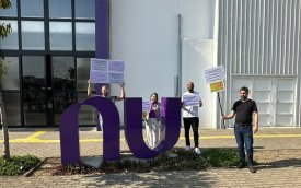 Imagem mostra dirigentes em frente ao prédio do Nubank. Eles seguram placas 