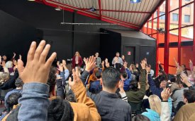Foto da assembleia, com mãos levantadas em aprovação ao acordo