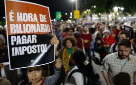 Foto de uma manifestação, na qual mulher segura um carta com a frase "é hora de bilionário pagar imposto"