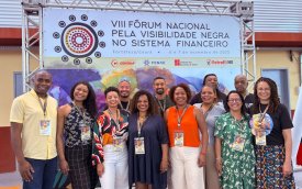 Imagem mostra membros do coletivo de combate ao racismo do Sindicato dos Bancáiros de São Paulo em frente a um painel do VIII Fórum Nacional pela Visibilidade Negra no Sistema Financeiro 