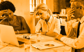 Imagem mostra três pessoas com semblante preocupado em frente a uma tela de computador