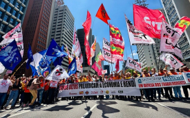 Imagem mostra manifestantes portando bandeiras de centrais sindicais e faixas durante protesto pela redução da taxa de juros