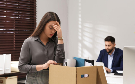 Imagem de uma mulher juntando suas coisas em uma caixa de papelão em um escritório