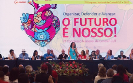 Imagem mostra dirigentes lado a lado no palco do 7º Congresso Nacional da Contraf-CUT. Atrás deles há um telão imenso com uma arte formada por um coração estilizado ao lado do texto "O Futuro é Nosso"