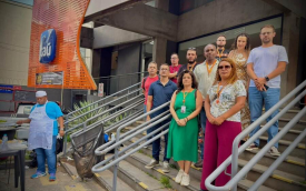 Imagem mostra dirigentes sindicais perfilados na escada em frente a uma agência do Itaú. Ao lado deles, um homem assa uma sardinha em uma grelha