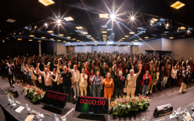 Imagem mostra auditório lotado de bancários com os braços erguidos durante a conferência nacional dos bancários