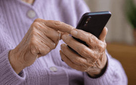 Imagem das mãos de uma mulher idosa teclando em um celular