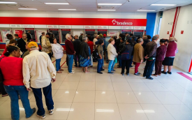 Imagem mostra agêencia lotada de idosos na área do autoatendimento