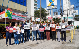 Imagem mostra trabalhadores protestando em frente a uma agência da Caixa