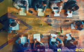 Imagem mostra pessoas em torno de uma mesa, vistas de cima