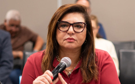 Foto da presidenta do Sindicato dos Bancários de São Paulo, Neiva Ribeiro, com uma camisa vermelho, segurando o microfone, na mesa de negociação com a Fenaban
