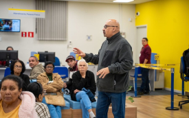 Imagem mostra o dirigente sindical João Maia (um homem branco, careca e de cerca de 50 anos), conversando com populares dentro de uma agência lotada do Banco do Brasil