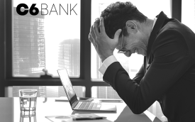 Imagem de um bancário, de cabeça baixa, em postura de desespero, na frente de um computado