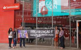 Dirigentes sindicais protestam contra terceirizações no Santander, na avenida Paulista. Eles estão em frente a uma agência e seguram uma faixa escrita "terceirização é sinônimo de precarização"