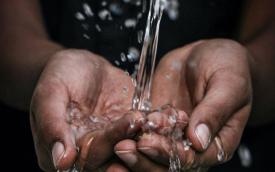 Imagem de um fluxo de água caindo nas palmas das mãos de uma pessoa