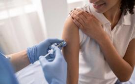 Imagem mostra uma mulher sendo vacinada por outra mulher