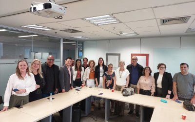 Pessoas em pé ao atrás da mesa antes da assinatura do acordo do Santander