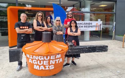 Imagem mostra dirigentes e funcionários do Sindicato em frente a uma agência do Itaú durante protesto contra assédio moral e demissões